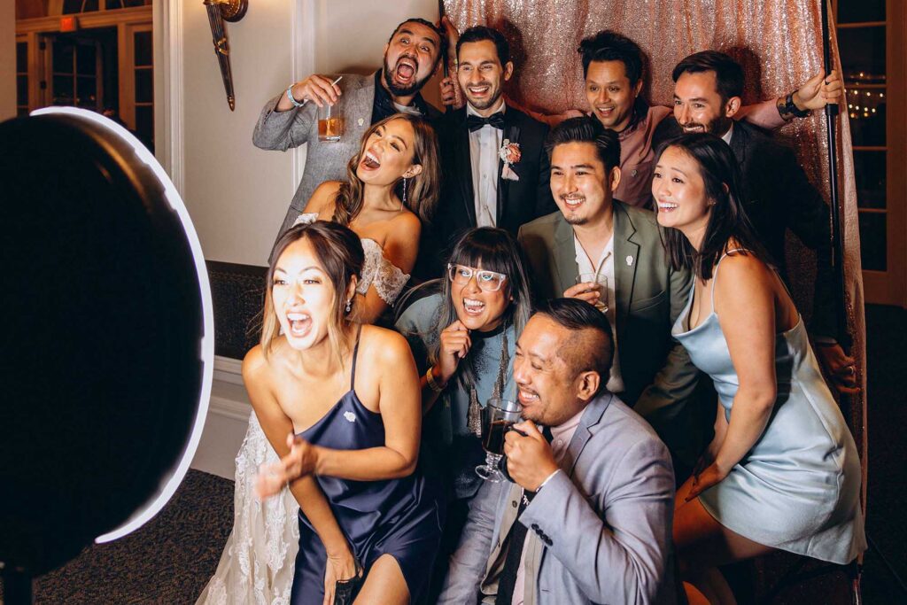 Group of event guests laughing and posing inside a modern photo booth.